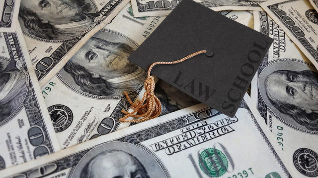 Law school graduation cap on pile of cash