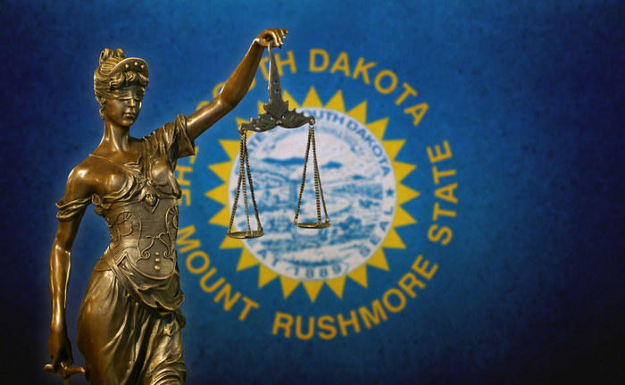 Lady Justice before a South Dakota state flag